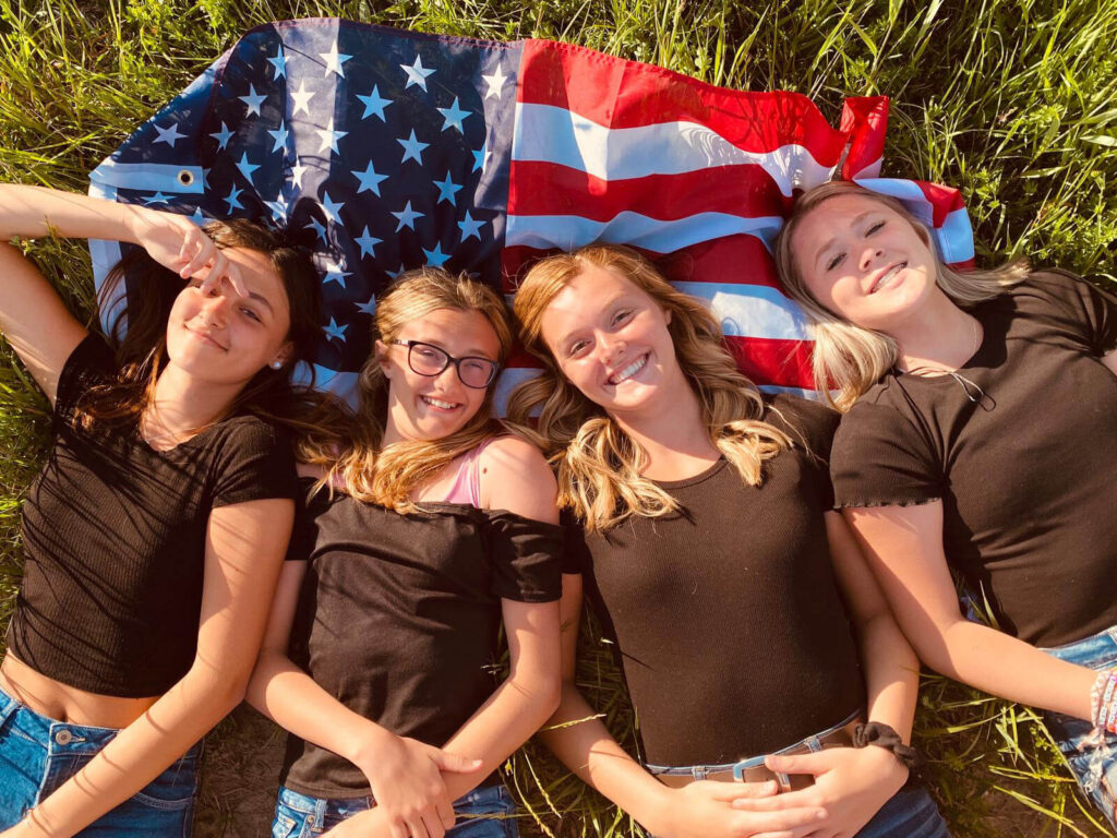 modulo familia programa colegio publico familia USA J1 amigas sobre la hierba con bandera estudiante TLT